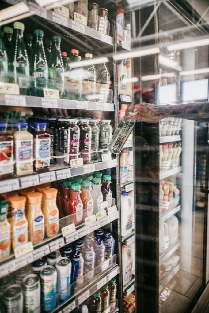 Shopper selecting a product from a stocked chiller shelf